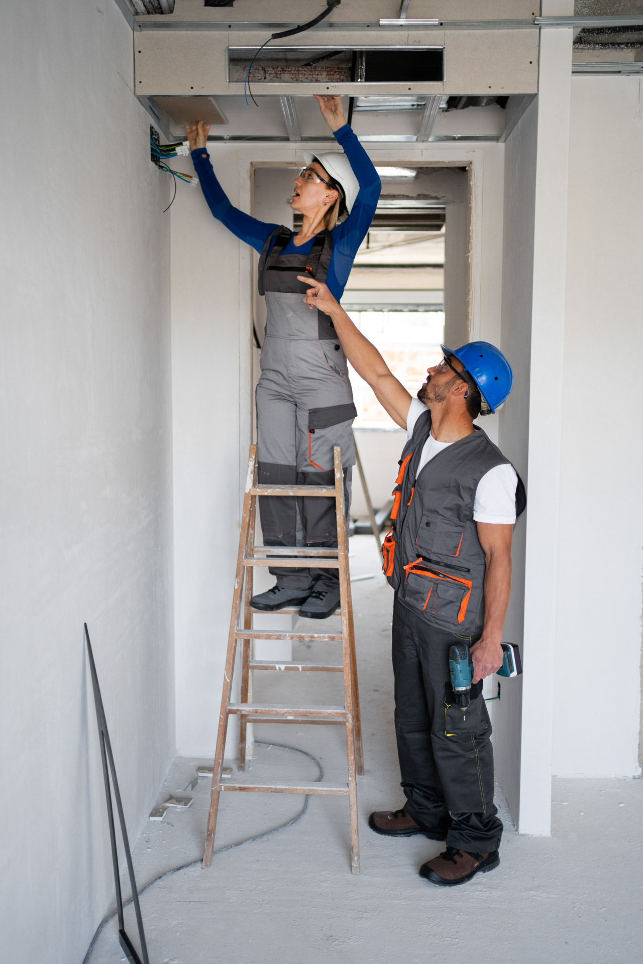 two handyman fixing wires in the ceiling